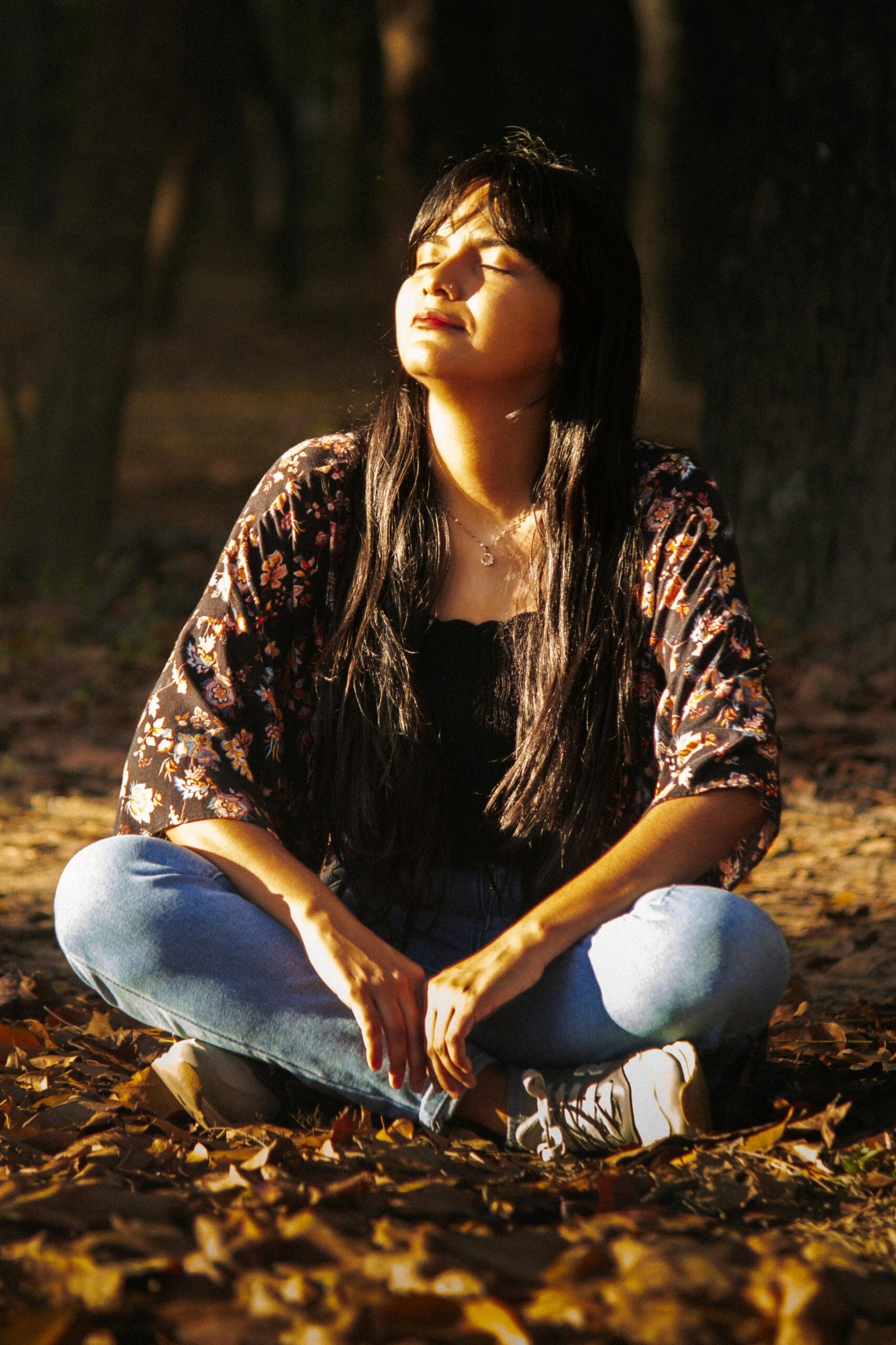 A woman enjoying peaceful moments in nature, basking in warm autumn sunlight.
